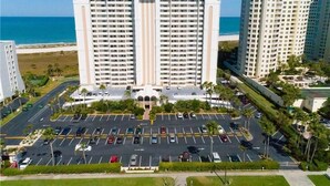 A high-rise hotel with a central courtyard, parking lot, and ocean view. - Paradise on the beach in an oceanfront, luxury condo on Sand Key (Clearwater Beach)