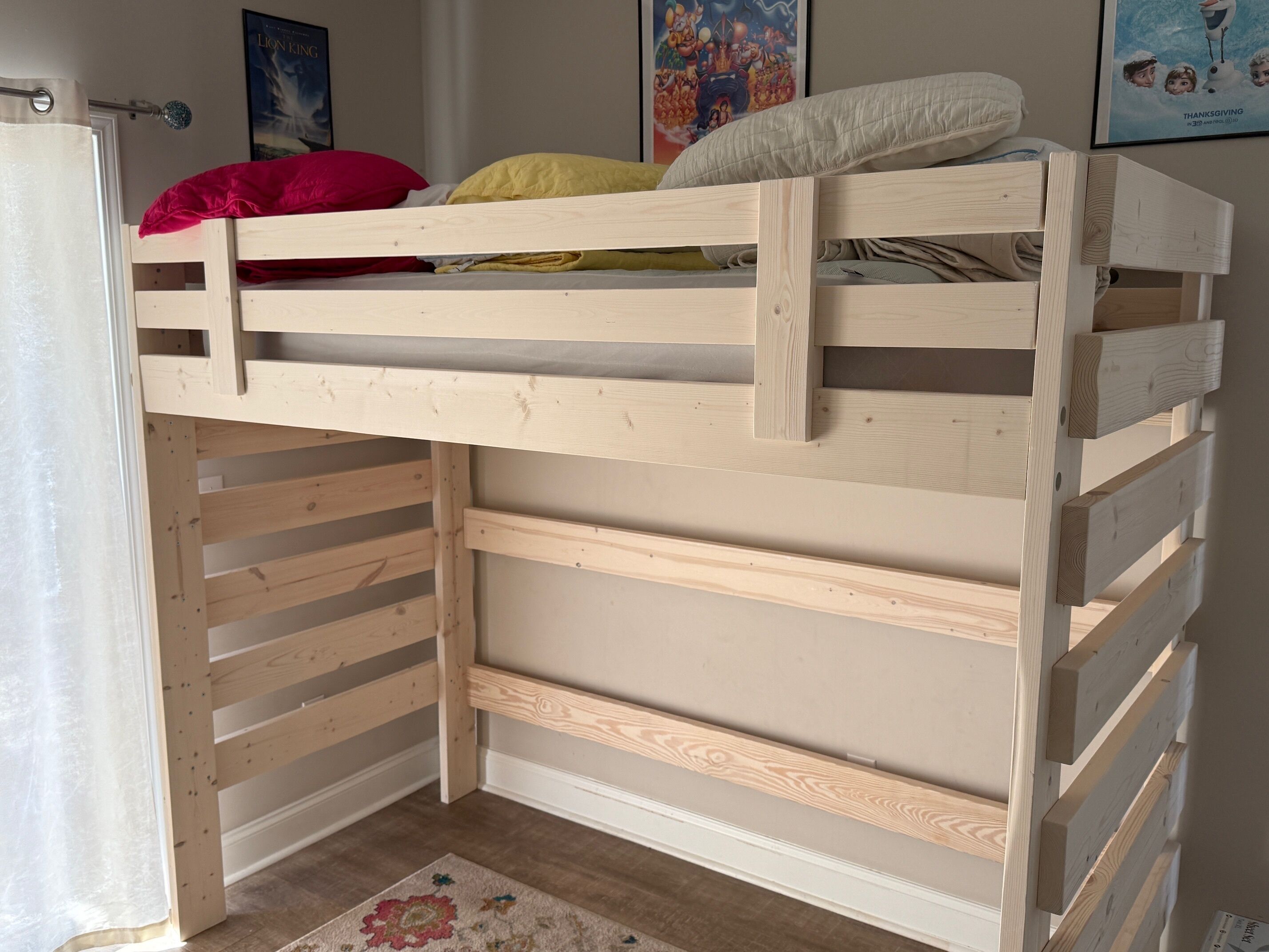 Uma cama de beliche com ripas de madeira, um travesseiro branco e um travesseiro vermelho no colchão superior.