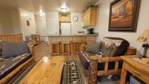 L’intérieur d’un chalet rustique comprend un coin repas en bois, un canapé et une cuisine avec des meubles blancs.