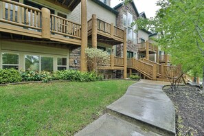 A multi-story building with wooden balconies, a concrete pathway, and a well-maintained lawn. - 4 Bedroom 3 bath easiest access to hot tub (Eden)