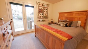 A bedroom with a wooden bed, a dresser, a window with a view, and a wall decoration. - 4 Bedroom 3 bath easiest access to hot tub (Eden)
