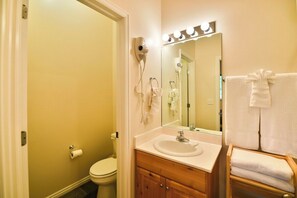 A bathroom with a toilet, sink, vanity, and a mirror with lights. - 4 Bedroom 3 bath easiest access to hot tub (Eden)