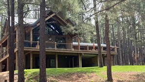 Eine große Holzhütte mit Balkon, umgeben von hohen Kiefern.