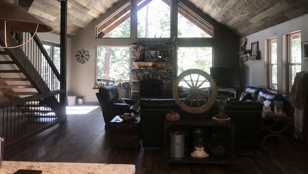 Ein rustikales Interieur mit Kamin aus Stein, Holzbalkendecke und einer gemütlichen Sitzecke mit einer großen Holzscheibe als Dekoration.