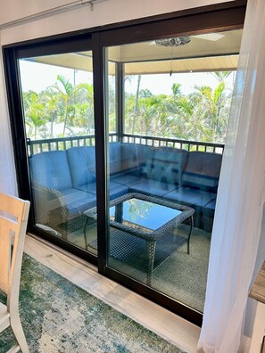 Un balcon avec une porte-fenêtre, un ensemble de canapés et une petite table.