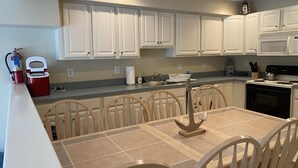 A modern kitchen with white cabinets, a dining table with chairs, and a built-in oven. - Just steps from the Beach and Boardwalk! Perfect vacation getaway! (North Wildwood)