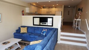 A living room with a blue sofa, a white coffee table, and a flat-screen TV mounted above the sofa. - Just steps from the Beach and Boardwalk! Perfect vacation getaway! (North Wildwood)