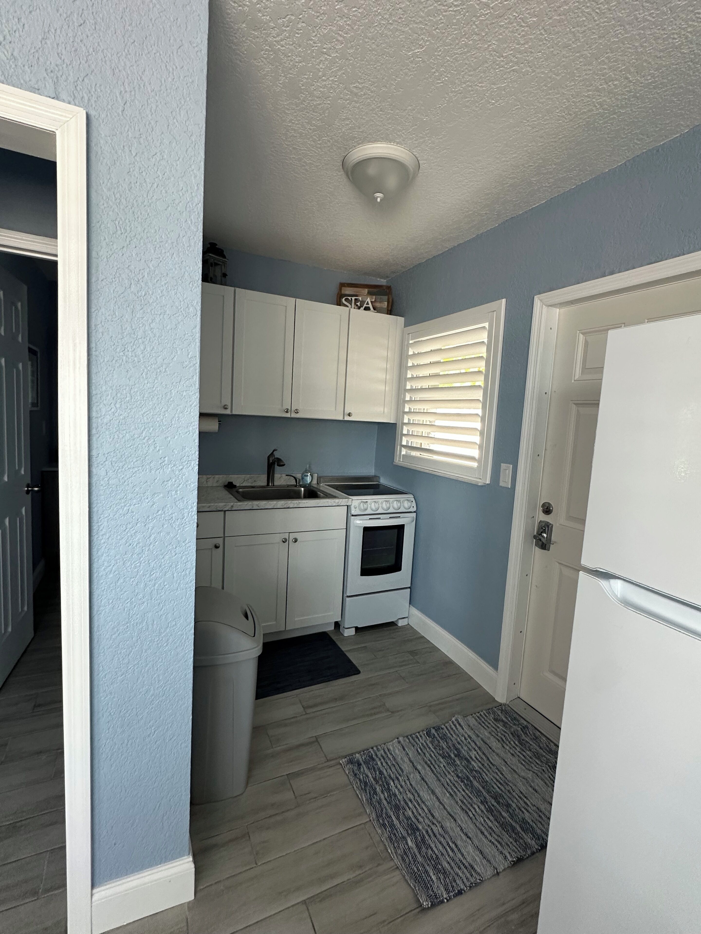 A compact kitchen with white cabinets, a stove, and a refrigerator.