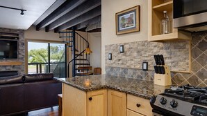 A modern kitchen with wooden cabinets, a granite countertop, and a stainless steel stove.