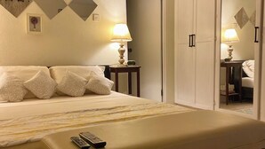 Una habitación de hotel con cama, mesita de noche, lámpara y un banco.
