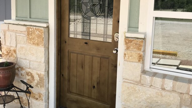 Una puerta de madera marrón con un panel de vidrio y un pomo en forma de estrella de metal.