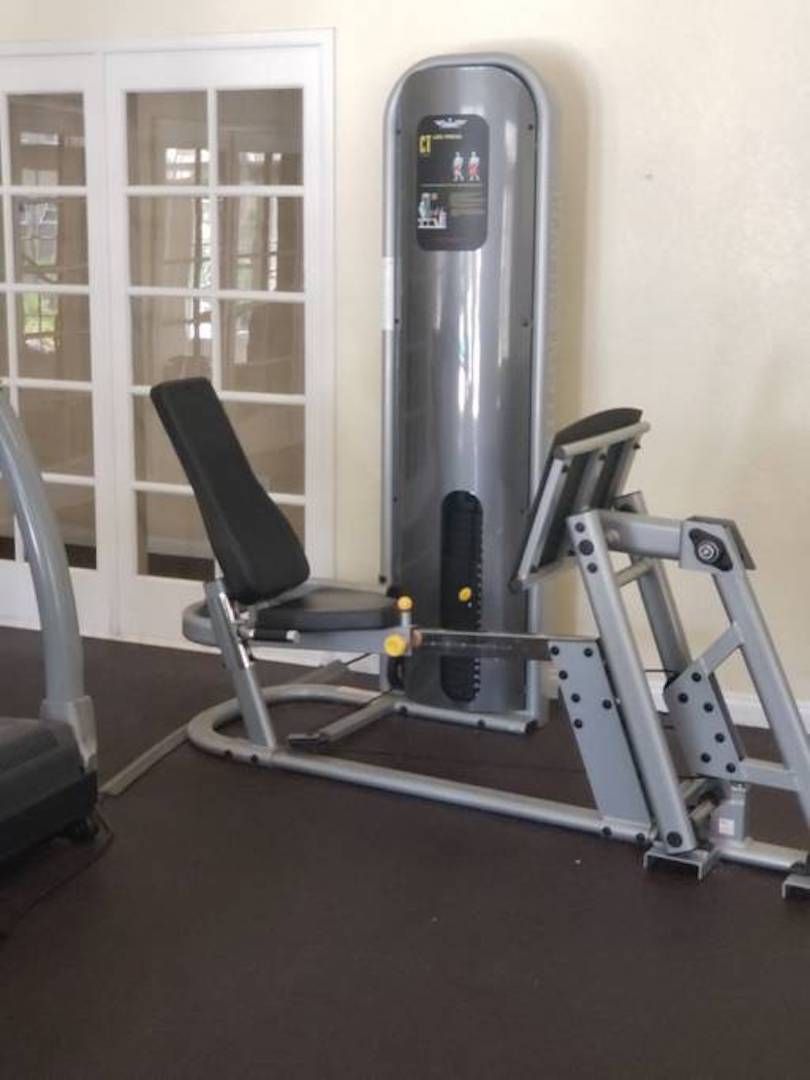 Et fitnessrum med en bænkpres, en brystpressmaskine og et vægmonteret display.
