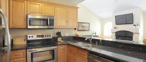 A modern kitchen with wooden cabinets, stainless steel appliances, and a large window.