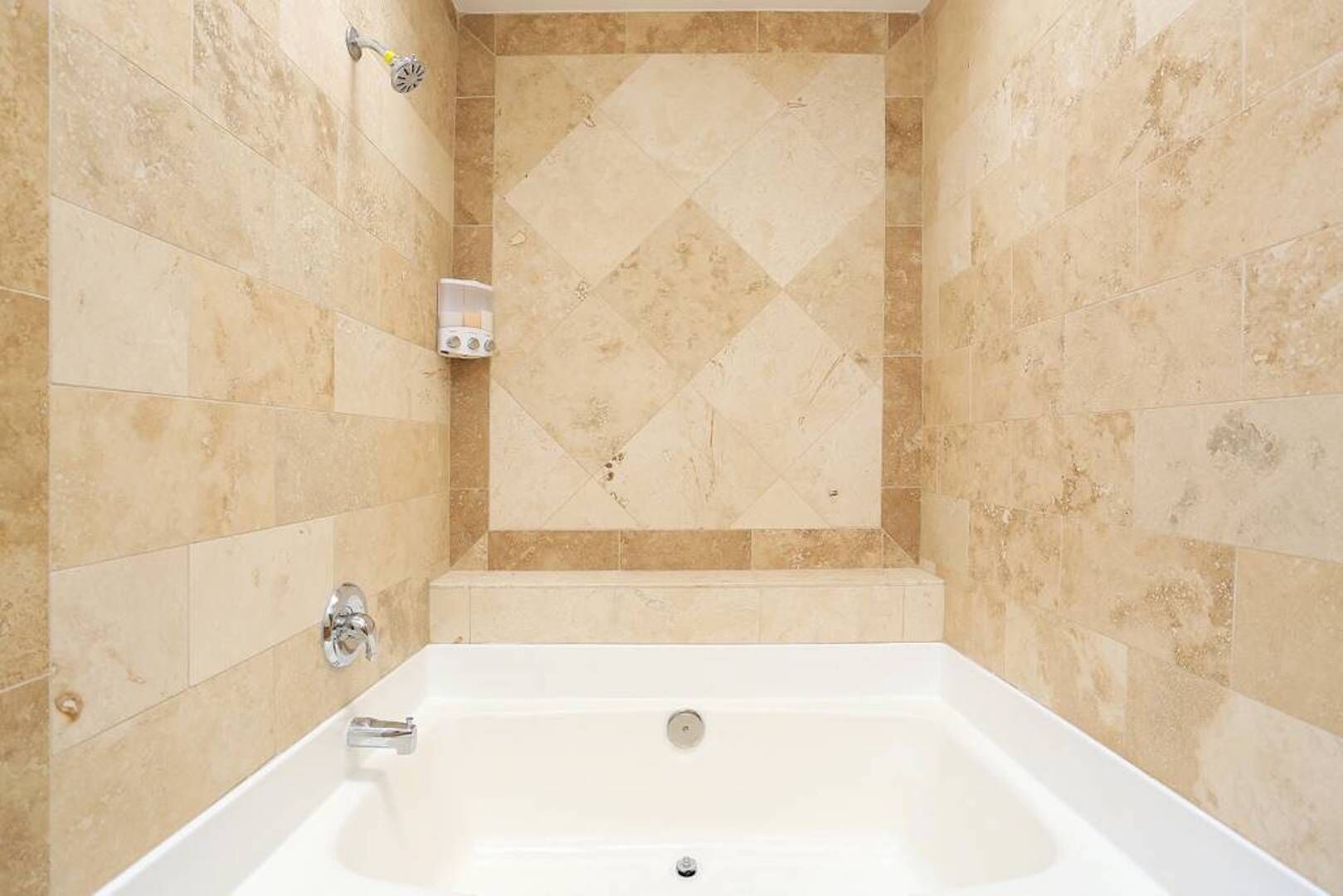 A bathroom with a bathtub, tiled walls, and a shower area.