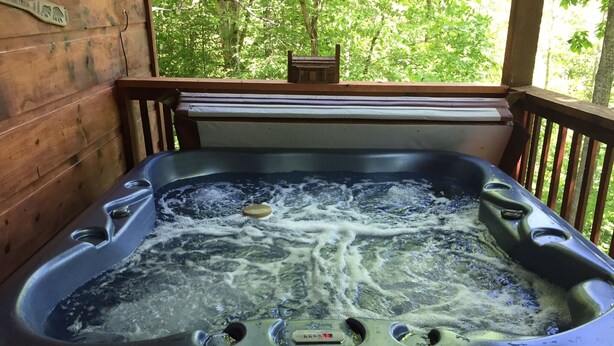 Un bain à remous sur une terrasse en bois, avec vue sur les arbres.