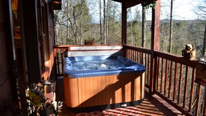 Un bain à remous en bois installé sur une terrasse, avec vue sur une forêt.