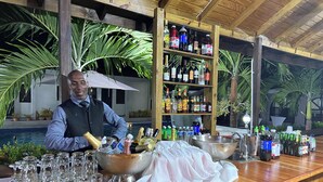 Un espace bar avec un barman, un grand récipient rempli de glace, ainsi qu’une variété de bouteilles et de verres.