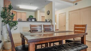 Un comedor con una mesa de madera, dos sillas, un banco y una planta en maceta.
