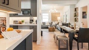 Une cuisine moderne dotée d’un îlot central, un coin repas avec une table en bois et un salon avec un canapé et une table basse.