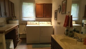 Una cocina con lavadora y secadora integradas, un lavamanos con encimera de mármol y armarios de madera.