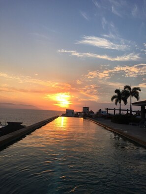 Une longue et étroite piscine, avec un coucher de soleil en arrière-plan.