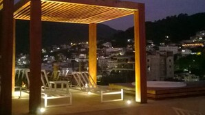 Ein Gazebo mit Blick auf eine nächtliche Stadtlandschaft.