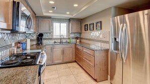 A modern kitchen with stainless steel appliances, wooden cabinets, and a tiled backsplash. - Station One - 8I From - Oceanfront condo with community pool, tennis, beach (Wrightsville Beach)