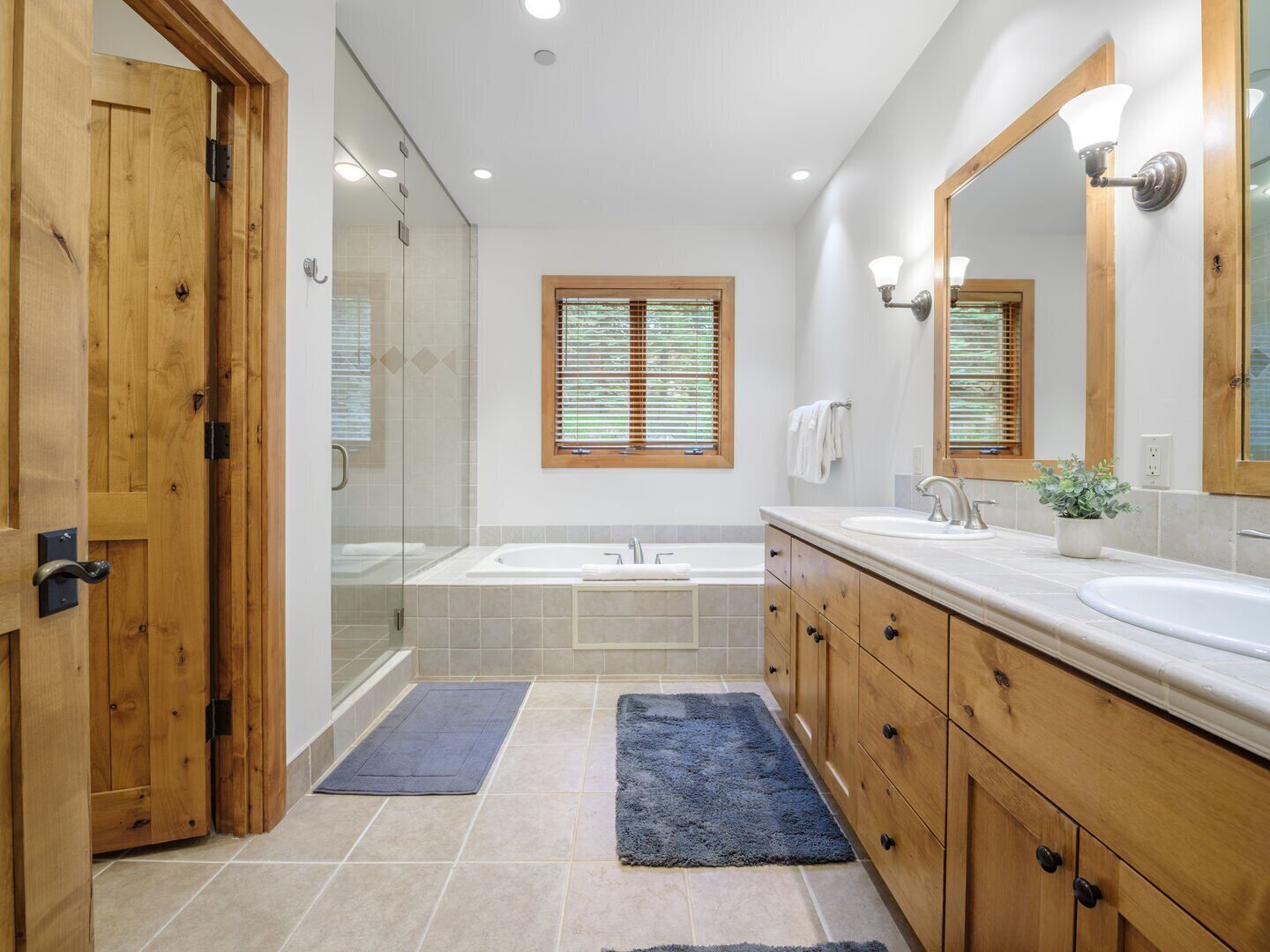 A modern bathroom with a glass shower enclosure, a double sink vanity, and a large mirror.