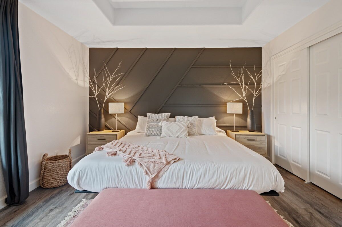 Un dormitorio con una cama grande, dos mesitas de noche, un banco y un techo con diseño inclinado.