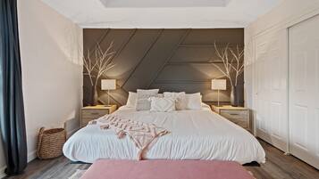 Un dormitorio con una cama grande, dos mesitas de noche, un banco y un techo con diseño inclinado.