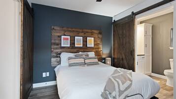 Un dormitorio con cama, cabecera de madera y puerta que da a un baño.