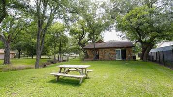 A picnic table in a grassy area with a stone building in the background.