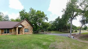 A stone building with a sloped roof, a front porch, and a well-maintained lawn.