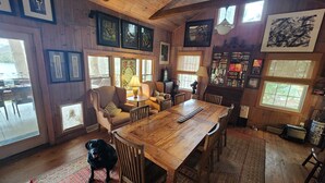 Un intérieur chaleureux, avec des murs en bois, une table à manger, des chaises, un canapé et un chien.