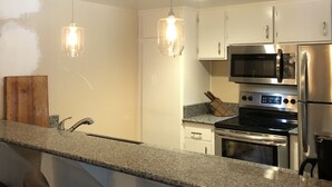 A modern kitchen with granite countertops, stainless steel appliances, and pendant lighting. - Horizons single story ground floor 2 bdrm (Mammoth Lakes)
