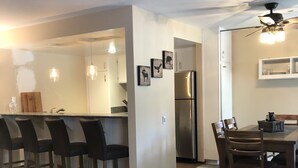 A modern kitchen with a central island, bar stools, a dining table with chairs, and a refrigerator. - Horizons single story ground floor 2 bdrm (Mammoth Lakes)