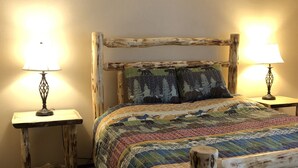A bedroom with a wooden bed frame, two bedside tables with lamps, and a colorful quilt. - Horizons single story ground floor 2 bdrm (Mammoth Lakes)