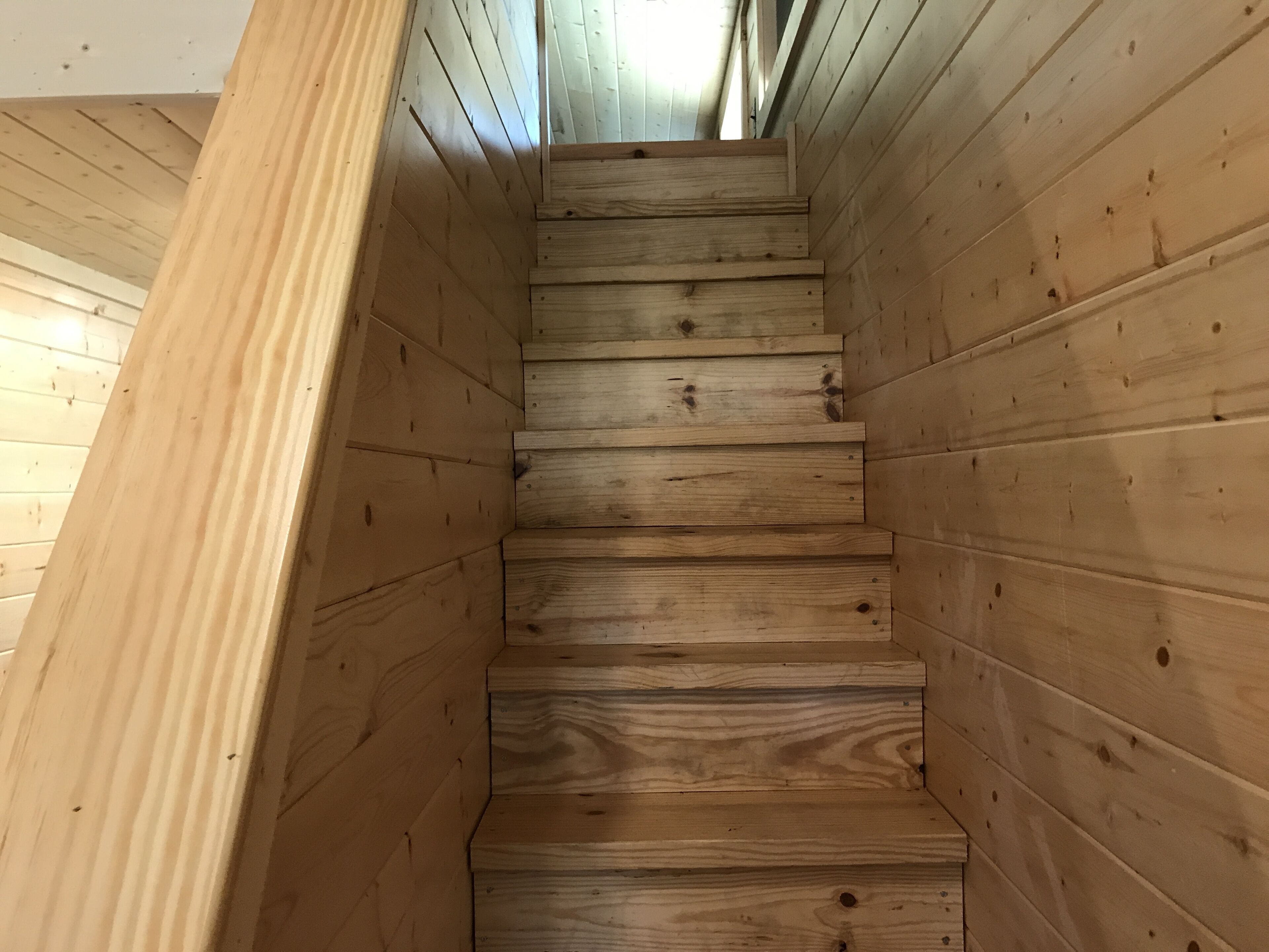 Una escalera de madera con barandilla a la izquierda que sube a un piso superior.