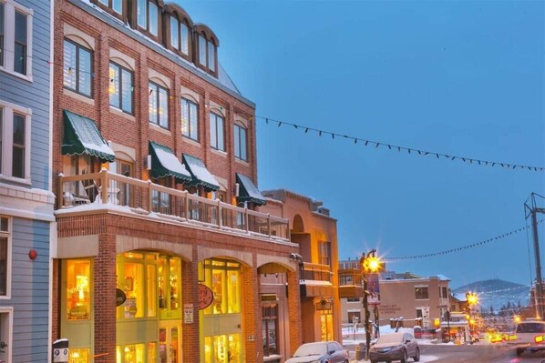 A multi-story building with a brick facade, large windows, and a balcony with a railing.