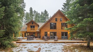 A log cabin with a deck, outdoor seating, and a snow-covered ground.