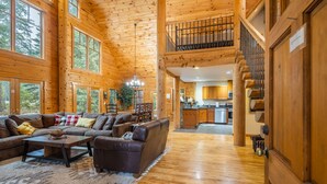 A spacious wooden interior with a living area, kitchen, and a staircase leading to a loft.