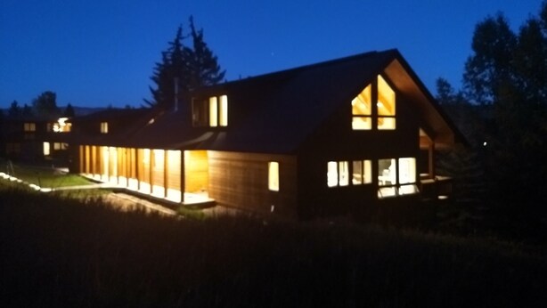 Una casa moderna con ventanas amplias e iluminación exterior al anochecer.