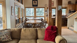 Una sala de estar acogedora con un sofá, una mesa de centro y una zona de comedor con un ventanal grande.