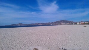 A wide sandy beach with a clear blue sky and distant hills. - Beautiful Remodeled Condo near DownTown and Beach in San Jose del Cabo. (San Jose del Cabo,B.C.S.23406)