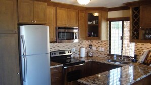 A kitchen with wooden cabinets, stainless steel appliances, a granite countertop, and a window with blinds. - Beautiful Remodeled Condo near DownTown and Beach in San Jose del Cabo. (San Jose del Cabo,B.C.S.23406)