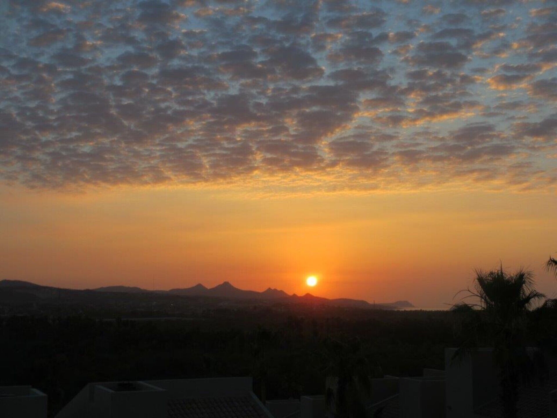 A sunset over a cityscape with mountains in the background.