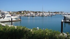 A marina with multiple boats docked, surrounded by greenery and buildings in the background. - Beautiful Remodeled Condo near DownTown and Beach in San Jose del Cabo. (San Jose del Cabo,B.C.S.23406)
