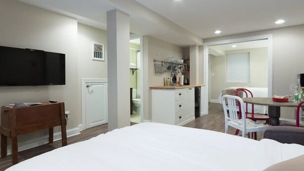 A modern bedroom with a large bed, a TV, a wooden desk, and a kitchenette. - Charming H St Oasis close to Capitol and museums (Washington)