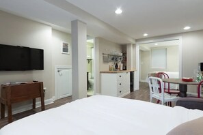 Een moderne slaapkamer met een groot bed, een televisie, een houten bureau en een kitchenette.