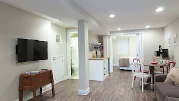 A compact living space with a TV, a dining area, and a kitchenette.